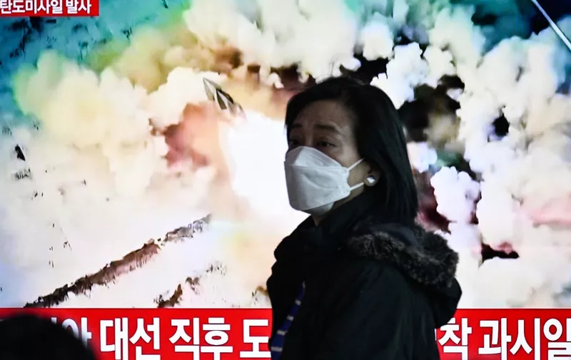 A woman walks past a television showing a news broadcast with file footage of a North Korean missile test, at a railway station in Seoul on March 18, 2024. North Korea fired a ballistic missile on March 18, Seoul's military said, as US Secretary of State Antony Blinken visited South Korea to meet top officials and attend a democracy summit. (Photo by Anthony WALLACE / AFP)