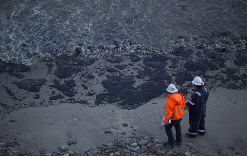 GOLETA, CALIFORNIA - MAY 19: Officials walk along an the oil-covered beach on May 19, 2015 north of Goleta, California. About 21,000 gallons spilled from an abandoned pipeline on the land near Refugio State Beach, spreading over about four miles of beach within hours. The largest oil spill ever in U.S. waters at the time occurred in the same section of the coast in 1969 where numerous offshore oil platforms can be seen, giving birth to the modern American environmental movement.   David McNew/Getty Images/AFP