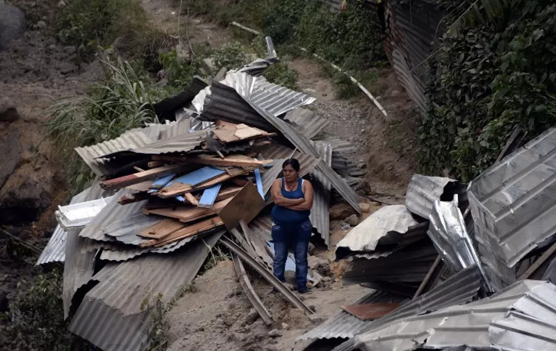 A woman stands amid the debris after a landslide late Thursday, following heavy rains, covered part of the village of El Cambray II, in Santa Catarina Pinula municipality, some 15 km east of Guatemala City, on October 2, 2015. At least nine people were killed and about 600 others missing following a landslide that damaged some 125 homes on the outskirts of the Guatemalan capital, an official said Friday, noting that the death toll could rise as rescue efforts continue.   AFP PHOTO / JOHAN ORDONEZ