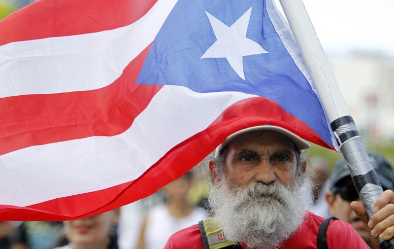 A man carries a Puerto Rican flag during a protest against the referendum for Puerto Rico political status in San Juan, on June 11, 2017.
To become a true US state, to choose independence or to maintain the status quo: Puerto Ricans went to the polls to consider their political future in a non-binding referendum many have vowed to boycott. / AFP PHOTO / Ricardo ARDUENGO