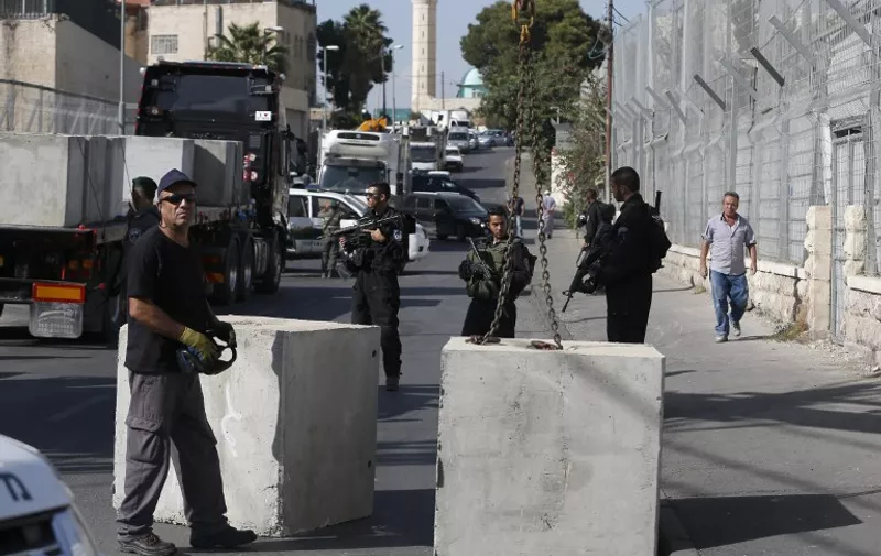 Israeli security forces gather at the site where a road block is being set up on a road close to the Palestinian neighbourhood of Ras al-Amud  in east Jerusalem, on October 14, 2015. Israel set up checkpoints in Palestinian neighbourhoods of east Jerusalem and mobilised hundreds of soldiers as it struggled to stop  attacks that have raising fears of a full-scale uprising.  AFP PHOTO / AHMAD GHARABLI