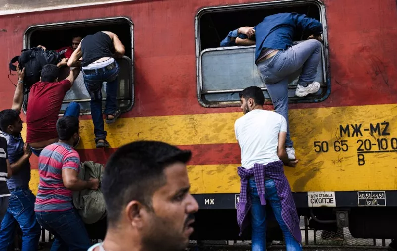 Migrants try to get on a train heading to the border with Serbia at the train station in Gevgelija, on the Macedonian-Greek border on August 7, 2015. Some 224,000 migrants and refugees have crossed the Mediterranean to Europe so far this year, the UN said. AFP PHOTO / DIMITAR DILKOFF