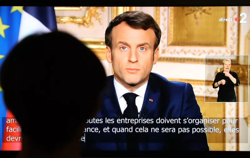 French President Emmanuel Macron is seen on a television screen as he speaks during a televised address to the nation on the outbreak of COVID-19, caused by the novel coronavirus, on March 16, 2020, in Paris. - The French president addresses the nation, with many expecting him to unveil more strict home confinement rules in a bid to prevent the virus from spreading. France has closed down all schools, theatres, cinemas and a range of shops, with only those selling food and other essential items allowed to remain open. The balance sheet of the epidemic climbed to 127 dead and 5,423 confirmed cases in France. (Photo by Ludovic Marin / AFP)