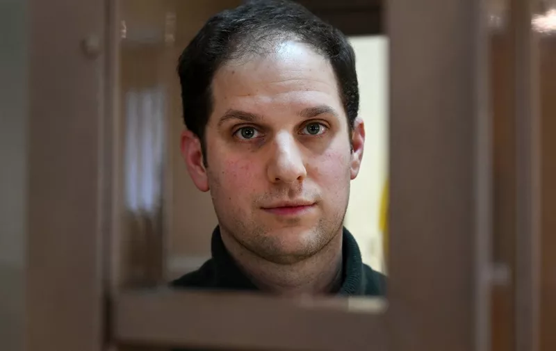 (FILES) US journalist Evan Gershkovich, arrested on espionage charges, looks out from inside a defendants' cage before a hearing to consider an appeal on his extended pre-trial detention, at the Moscow City Court in Moscow on February 20, 2024. Evan Gershkovich, a Wall Street Journal reporter who has spent a year behind bars in Russia, is awaiting a trial on espionage charges the White House says are fabricated but could still see him jailed for decades. The US-born son of Soviet emigres covered Russia for six years. His arrest in March 2023 for spying is the first such charge against a Western journalist since the Soviet-era. The 32-year-old, who has been remanded in custody until at least the end of June, faces up to 20 years prison if found guilty. (Photo by NATALIA KOLESNIKOVA / AFP)