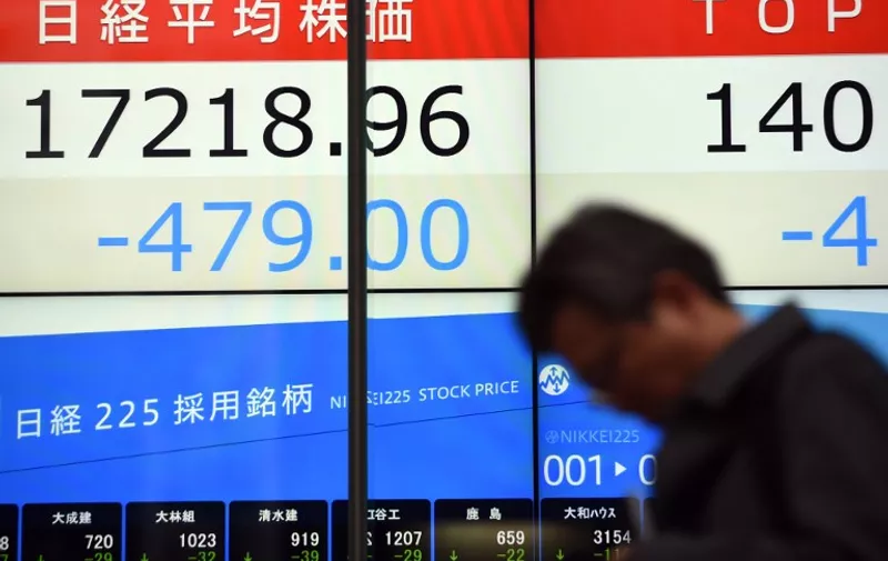 A businessman walks past a stock market indicator flashing the closing numbers from the Tokyo stock market in Tokyo on January 12, 2016. Tokyo shares fell 2.71 percent, or 479.00 points, to 17,218.96, the lowest close since late September, hit by a strong yen as dealers returned from a public holiday to play catch-up with another China-fuelled regional sell-off.      AFP PHOTO / TOSHIFUMI KITAMURA / AFP / TOSHIFUMI KITAMURA