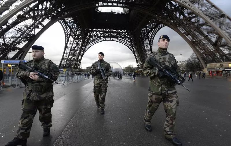 French soldiers patrol in front of the Eiffel Tower on January 8, 2015 in Paris as the capital was placed under the highest alert status a day after heavily armed gunmen shouting Islamist slogans stormed French satirical newspaper Charlie Hebdo and shot dead at least 12 people in the deadliest attack in France in four decades. A  huge manhunt for two brothers suspected of massacring 12 people in an Islamist attack at a satirical French weekly zeroed in on a northern town Thursday after the discovery of one of the getaway cars. As thousands of police tightened their net, the country marked a rare national day of mourning for Wednesday's bloodbath at Charlie Hebdo magazine in Paris, the worst terrorist attack in France for half a century. AFP PHOTO / BERTRAND GUAY