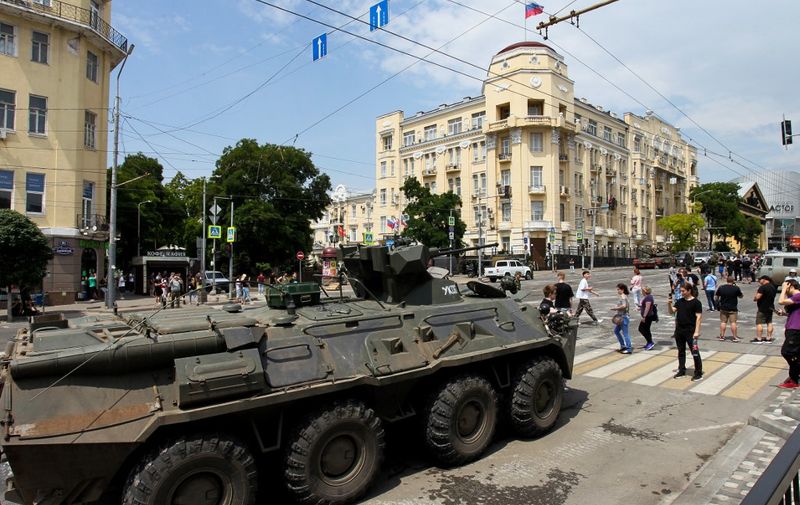 People walk past an armoured personnel carrier in the city of Rostov-on-Don, on June 24, 2023. President Vladimir Putin on June 24, 2023 said an armed mutiny by Wagner mercenaries was a "stab in the back" and that the group's chief Yevgeny Prigozhin had betrayed Russia, as he vowed to punish the dissidents. Prigozhin said his fighters control key military sites in the southern city of Rostov-on-Don. (Photo by STRINGER / AFP)