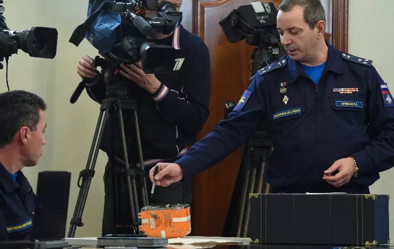 A Russian military official points to the flight recorder from the Russian Sukhoi Su-24 bomber which was shot down by a Turkish jet on November 24, as he addresses the media during a briefing on the start of the black boxes decoding in Moscow on December 18, 2015. Russia on December 18 began examining the black box of its warplane that was shot down over Turkey's border with Syria, again contesting Ankara's claim it had violated Turkish airspace.  / AFP / VASILY MAXIMOV