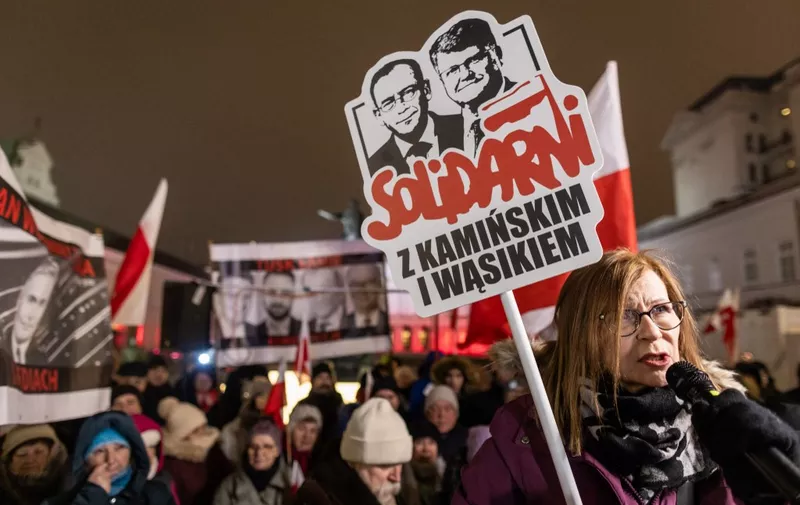 A woman holds a banner reading "Solidarity with Kaminski and Wasik" to protest in front of the Presidential Palace, Warsaw, January 10, 2024, where supporters of the Law and Justice (PiS) party take part in a demonstration in support of former Interior Minister Mariusz Kaminski and his deputy Maciej Wasik after their arrest. The arrests took place late in the presidential palace where Duda ally Mariusz Kaminski and his aide Maciej Wasik had spent several hours following an invitation from the president. (Photo by Wojtek Radwanski / AFP)