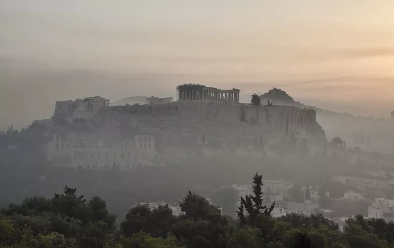 This photograph taken on August 4, 2021 shows smoke covering Athens centre with the Acropolis in the background, due to fires burning at the foot of Mount Parnes, 30 kilometres north of Athens. - Greek firefighters said in a statement that they hope to bring a forest fire blazing near Athens under control "in the coming hours". More than 500 firefighters, a dozen water-bombing planes and five helicopters have been battling the blazes outside the capital since August 3 afternoon. (Photo by LOUISA GOULIAMAKI / AFP)