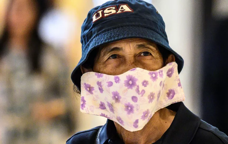 A shopper, wearing a protective facemask amid fears over the spread of the COVID-19 coronavirus, walks in a store in Bangkok on February 17, 2020. (Photo by Mladen ANTONOV / AFP)