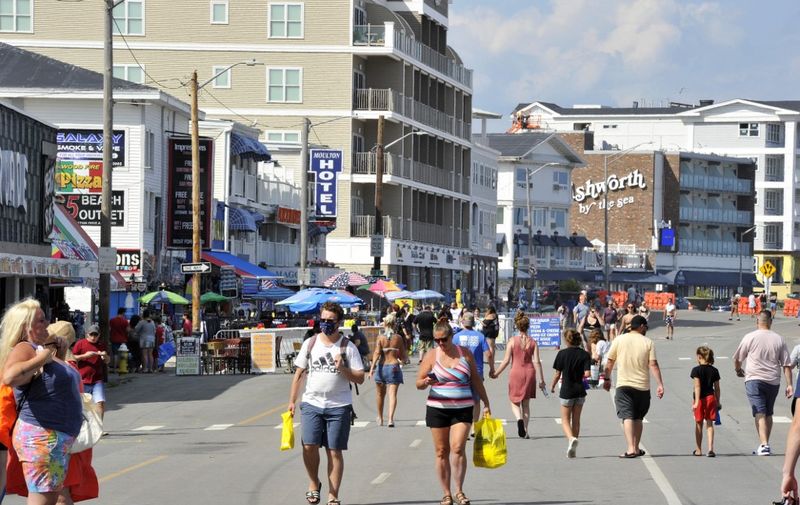 People, few wearing facemasks, walk on the boardwalk at Hampton Beach in Hampton, New Hampshire on August 5, 2020, as COVID-19 cases in New England are on the rise. - Hampton Beach is close to the boarder of Massachusetts and attracts thousands of people from Massachusetts every week to the New Hampshire beach and boardwalk. The US has now recorded 4,765,170 total cases of COVID-19 with 156,668 deaths, making it by far the worst-hit country in the world. (Photo by Joseph Prezioso / AFP)