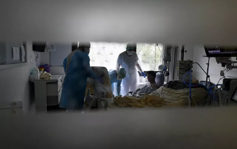 Medical staff tend to a patient infected with COVID-19 in the COVID reanimation unit at the Purpan hospital in Toulouse on February 4, 2021. (Photo by GEORGES GOBET / AFP)