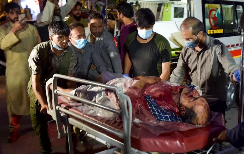 EDITORS NOTE: Graphic content / Volunteers and medical staff bring an injured man for treatment after two powerful explosions, which killed at least six people, outside the airport in Kabul on August 26, 2021. (Photo by Wakil KOHSAR / AFP)