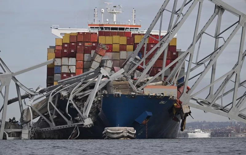 The steel frame of the Francis Scott Key Bridge sits on top of the container ship Dali after the bridge collapsed, Baltimore, Maryland, on March 26, 2024. The bridge collapsed early March 26 after being struck by the Singapore-flagged Dali, sending multiple vehicles and people plunging into the frigid harbor below. There was no immediate confirmation of the cause of the disaster, but Baltimore's Police Commissioner Richard Worley said there was "no indication" of terrorism. (Photo by Jim WATSON / AFP)