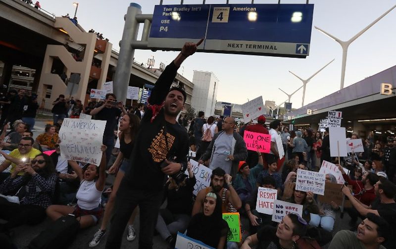 LOS ANGELES, CA - JANUARY 29: (EDITORS NOTE: Image contains profanity) Protesters chant as they block a road during a demonstration against the immigration ban imposed by U.S. President Donald Trump at Los Angeles International Airport on January 29, 2017 in Los Angeles, California. Thousands of protesters gathered outside of the Tom Bradley International Terminal at Los Angeles International Airport to denounce the travel ban imposed by President Trump. Protests are taking place at airports across the country.   Justin Sullivan/Getty Images/AFP