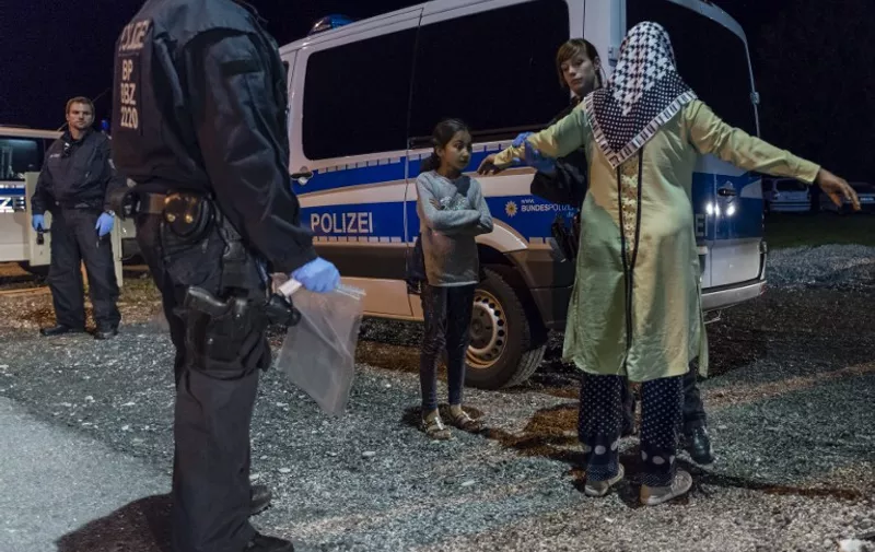 A policewoman controls a refugee mother and her daughter at the German-Austrian border near Piding, southern Germany, on September 14, 2015. After admitting that its capacity in the refugee crisis had been stretched to the limit, Berlin reintroduced identity checks on people travelling from the passport-free Schengen zone, and essentially announced an end to its open-doors policy to Syrians.     AFP PHOTO / GUENTER SCHIFFMANN