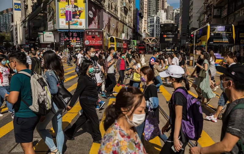 People wearing face masks as a preventative measure against the COVID-19 coronavirus cross a street in the Causeway Bay shopping district in Hong Kong on May 1, 2020. (Photo by DALE DE LA REY / AFP)