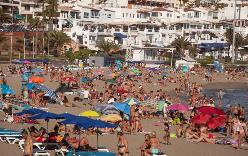Thousands of tourists sunbathe on the beach of Las Vistas in Los Cristianos on the southern coast of the Canary island of Tenerife, on July 25, 2015. Spain saw some 29.2 million foreign tourists visit in the first half of 2016, a new record for this key sector of its economy. More than a quarter (25.5%) of foreign visitors choose to stay in Catalonia  with the Canary Islands and the Balearic Islands and Andalusia in tow as favored destinations. AFP PHOTO / DESIREE MARTIN