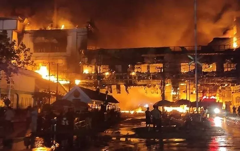 Firefighters and rescue workers gather at the site of a fire at the Grand Diamond City hotel-casino in Poipet on December 29, 2022. - As many as 10 people have died in a fire in a Cambodian hotel-casino on the border of Thailand, police said December 29. (Photo by AFP)