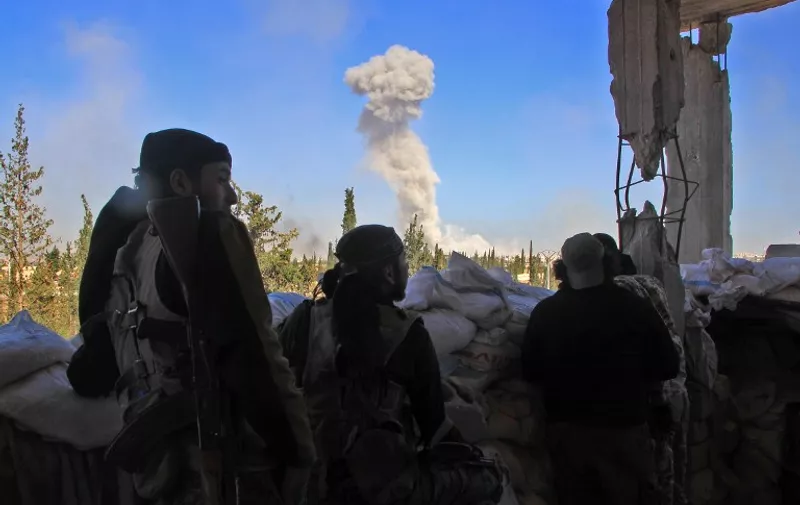 Rebel fighters from the Jaish al-Fatah (or Army of Conquest) brigades watch as smoke billows in the background on November 3, 2016, at an entrance to Aleppo, in the southwestern frontline near the neighbourhood of Dahiyet al-Assad, during a rebel offensive to break a three-month siege of the opposition-held east of Syria's second city. 
Syrian rebels launched a new wave of car bombs and rockets on Aleppo's western districts, redoubling their efforts to break the government's three-month siege of the city. / AFP PHOTO / Omar haj kadour