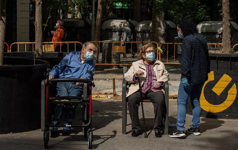 BARCELONA, SPAIN - MAY 02: An elderly man and woman wearing protective face masks sit on public benches as coronavirus lockdown restrictions eased on May 02, 2020 in Barcelona, Spain.  Spain continues to ease the Covid-19 lockdown measures this weekend, with high temperatures forecast across the country. Permitted activities now include walking with the family, outdoor exercise such as running from 6 - 10 AM and from 8 - 11 PM, going out with children from 12 - 7 PM and elderly people will be allowed to go out from 10 - 12 AM and from 7 - 8 PM. (Photo by David Ramos/Getty Images)