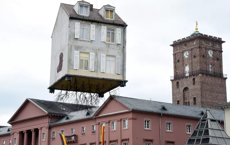 An installation by Argentinian artist Leandro Erlich titled "Pulled by the Roots" hangs on a crane on June 21, 2015 in Karlsruhe, southwestern Germany. The work is part of the exhibition "The City is the Star  Art at the Construction Site" running across the city until September 27, 2015.              AFP PHOTO / DPA / ULI DECK    +++    GERMANY OUY

RESTRICTED TO EDITORIAL USE, MANDATORY MENTION OF THE ARTIST UPON PUBLICATION, TO ILLUSTRATE THE EVENT AS SPECIFIED IN THE CAPTION
