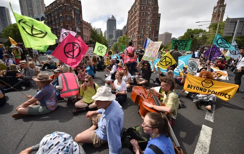 Extinction Rebellion activists stage a sit-in on a busy inner-city road in Sydney on October 7, 2019. - Extinction Rebellion activists began gathering in cities across Australia and New Zealand on October 7 to kick off a fortnight of global civil disobedience demanding governments take urgent action on climate change. (Photo by PETER PARKS / AFP)