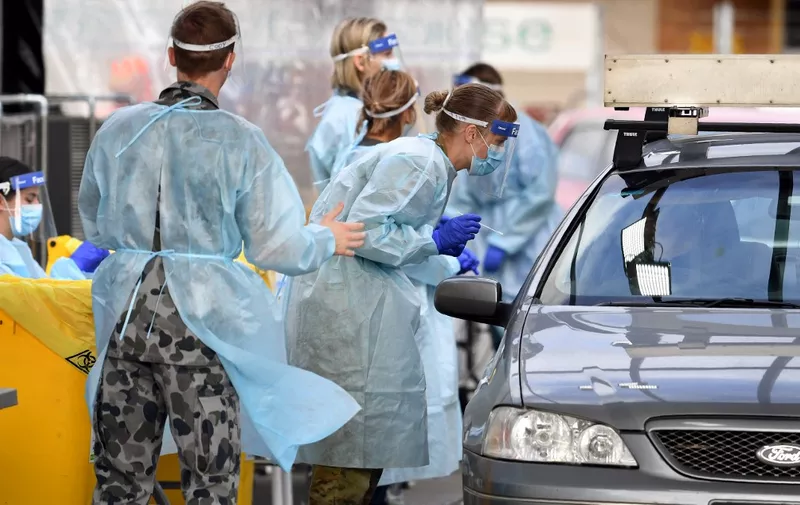 Members of the Australian Defence Force take a swab sample at a drive-through COVID-19 coronavirus testing station in the Melbourne suburb of Fawkner on July 2, 2020. - Around 300,000 people in Melbourne have to return to lockdown under the threat of fines and arrest as Australias second biggest city attempts to control a spike in virus cases. Health workers went door-to-door in the 36 Melbourne neighbourhoods targeted for lockdown, urging residents to be tested for the coronavirus. (Photo by William WEST / AFP)