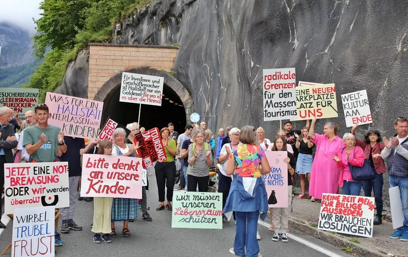 Locals protest against "overtourism" and block the road tunnel in the world-renowned sightseeing town of Hallstatt near Gmunden in Upper Austria on August 27, 2023. The placard read: "Visitors limitation, reclaim habitat"; "Radical limits for mass tourism"; "World culture at its end"; "Tourism Yes. Mass tourism No" (Photo by Reinhard HOERMANDINGER / APA / AFP) / Austria OUT