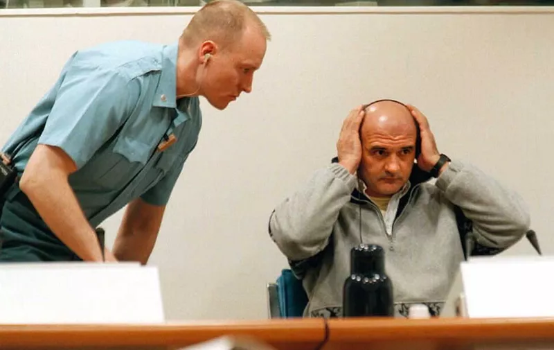 Forty-year-old Bosnian Croat Zdravko Mucic (R) adjusts his headphones before he is heard by the UN war-crimes tribunal on the former Yugoslavia, at The Hague 11 April. Mucic is charged with war crimes against Serbs, and has pleaded not guilty.
        AFP PHOTO Ed OUDENAARDEN (Photo by ED OUDENAARDEN / ANP / AFP)