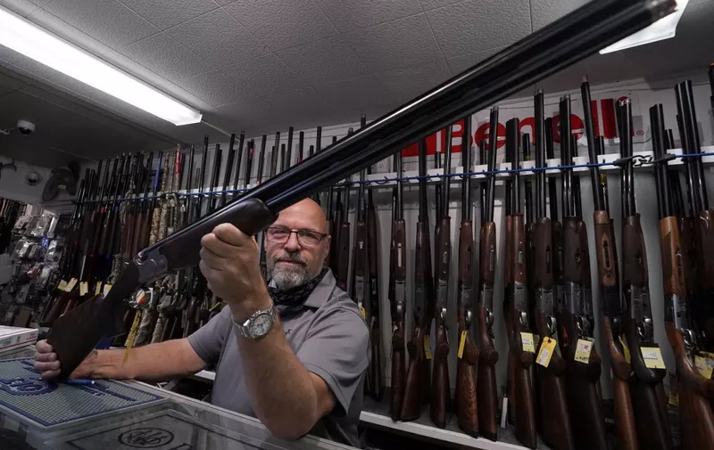(FILES) In this file photo taken on October 01, 2020 salesman Paul Fraker shows off weapons for sale at Coliseum Gun Traders Ltd. in Uniondale, New York. - US firearms makers produced over 139 million guns for the commercial market over the two decades from 2000, including 11.3 million in 2020 alone, according to a new government report. Another 71 million firearms were imported in the same period -- compared to just 7.5 million exported -- underscoring how the country is literally swimming in personal weapons that have stoked a surge in gun violence, murders and suicides, according to the Justice Department report. (Photo by TIMOTHY A. CLARY / AFP)