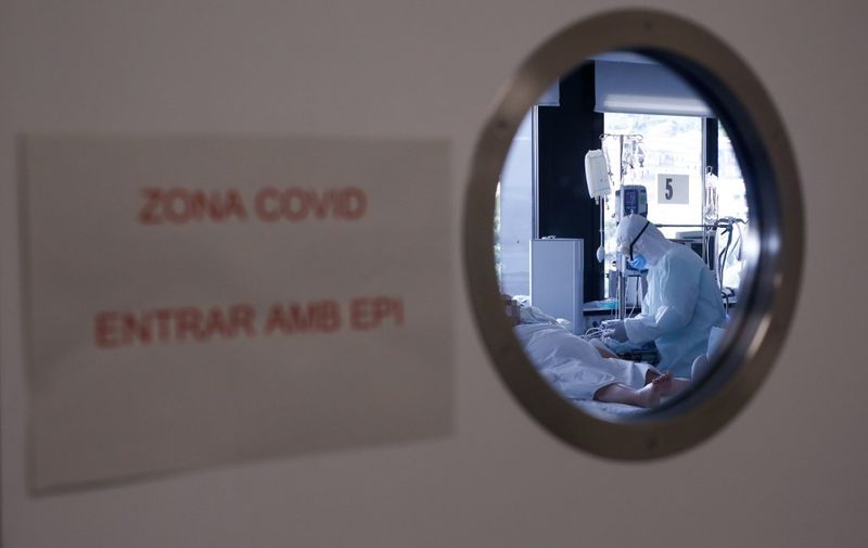 A healthcare worker wearing a protective suit attends to a COVID-19 coronavirus patient at the Intensive Unit Care (ICU) of the Vall d'Hebron Hospital in Barcelona on April 6, 2020. - Spain declared a fourth consecutive drop in the number of coronavirus-related deaths with 637 over the past 24 hours, the lowest number in nearly two weeks. (Photo by Pau Barrena / AFP)