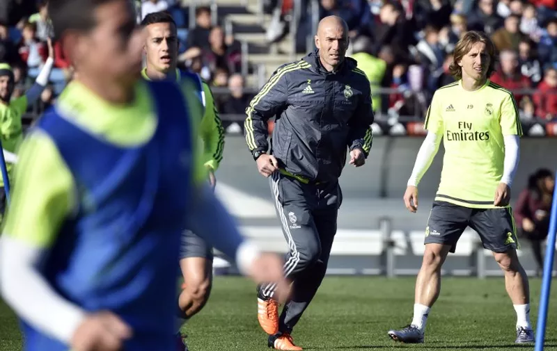 Real Madrid's new French coach Zinedine Zidane (C) runs past Real Madrid's Croatian midfielder Luka Modric (R) during his first training session as coach of Real Madrid at the Alfredo di Stefano stadium in Valdebebas, on the outskirts of Madrid, on January 5, 2016. Real Madrid legend Zinedine Zidane promised to put his "heart and soul" into managing the Spanish giants after he was sensationally named as coach following Rafael Benitez's unceremonious sacking. AFP PHOTO/ GERARD JULIEN / AFP / GERARD JULIEN