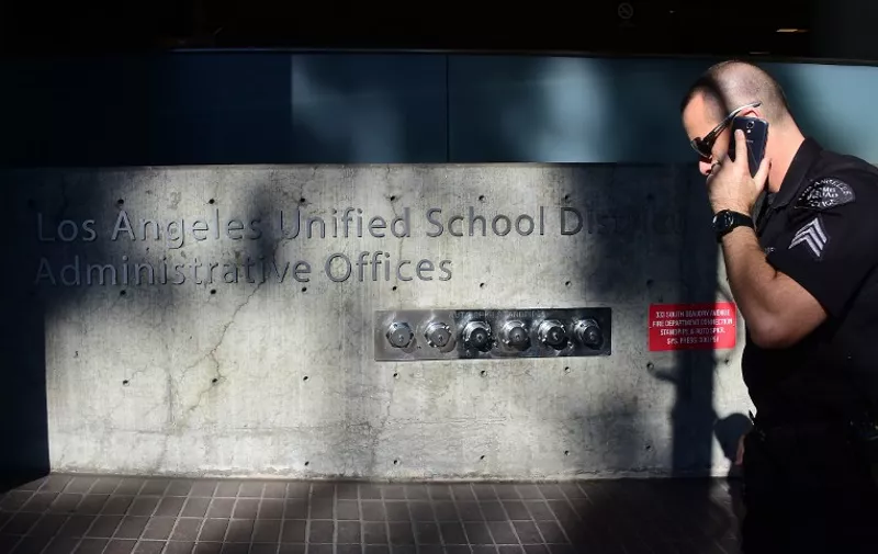 A police officer walks past the administrative offices of the Los Angeles Unified School District where schools superintendant Ramon Cortines,Mayor Eric Garcetti and police chief Charlie Beck addressed the media in Los Angeles, California on December 15, 2015.  The city of Los Angeles shut down all public schools on Tuesday after receiving a "credible" electronic threat targeting the country's second-largest education district and its 640,000 students. Ramon Cortines, the superintendent of Los Angeles schools, said the extraordinary measure was ordered as a precaution, triggered in part by the December 2 attacks in nearby San Bernardino. AFP PHOTO/ FREDERIC J. BROWN / AFP / FREDERIC J. BROWN