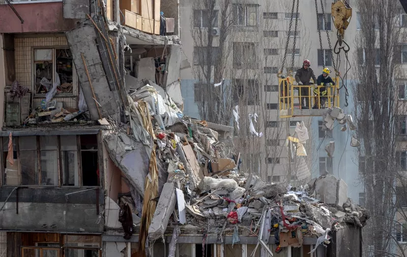 Rescuers clear debris from a multi-story building heavily damaged following a drone strike, in Odesa on March 3, 2024, amid the Russian invasion of Ukraine. Two more bodies have been found following a deadly Russian drone strike on the southern port city of Odesa, Ukraine said on March 3, 2024. The deaths of a woman and her eight-month-old baby take the toll to ten from the strike overnight between March 1, 2024 and March 2, 2024. (Photo by Oleksandr GIMANOV / AFP)