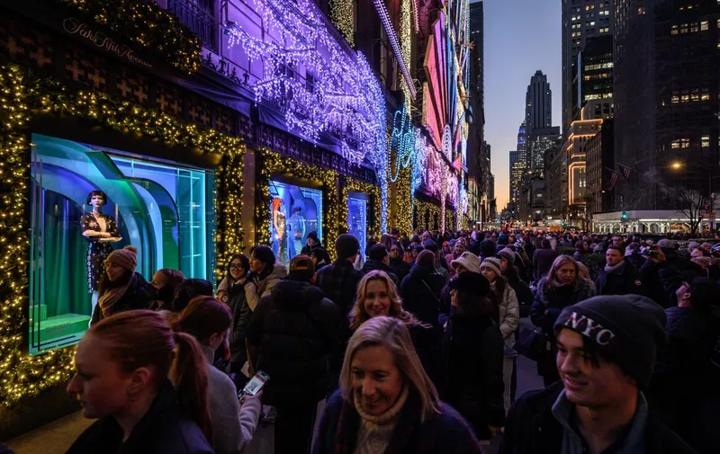 Shoppers and tourists walk before the Saks Fifth Avenue department store in New York on December 21, 2022. (Photo by Ed JONES / AFP)
