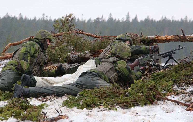 Soldiers from the Swedish Army's Gotland regiment load a machine gun on a range on the island of Gotland on February 5, 2019. - Following the annexation of Crimea, the conflict in Ukraine, incidents of Russian military jets approaching Swedish aircraft around the Baltic and the 2014 sighting of a mystery sub - suspected to be Russian, which Moscow denied - near Stockholm, Sweden has scrambled to beef up a military that was cut back after the end of the Cold War. (Photo by Tom LITTLE / AFP)
