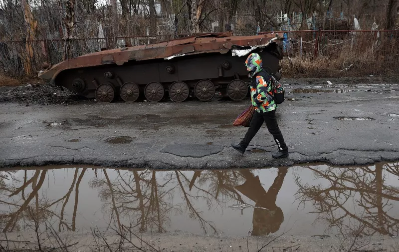 A woman walk past a destroyed armoured military vehicle in the Svyatogirsk town, Donetsk region, on January 27, 2024, amid the Russian invasion of Ukraine. (Photo by Anatolii STEPANOV / AFP)
