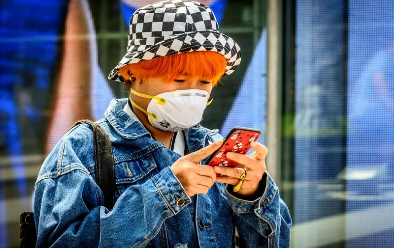 A woman wearing a protective facemask checks her mobile phone outside a shopping mall in Bangkok on February 4, 2020. - Thailand so far has detected 19 confirmed cases of the novel coronavirus believed to have originated in the central Chinese city of Wuhan, which is under lockdown. (Photo by Mladen ANTONOV / AFP)
