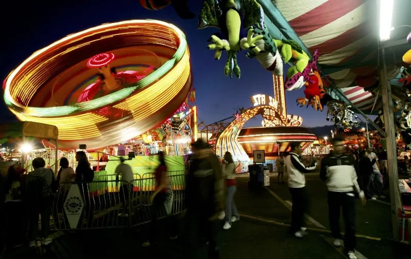 Fair-goers enjoy rides and games at dusk during the San Diego County Fair 29 June 2005 in Del Mar, California. The fair features games, rides, live entertainment, livestock shows, food and much more and is one of the 10 largest fairs in North America.  (Photo by Sandy Huffaker/Getty Images/AFP) FOR NEWSPAPERS AND TV USE ONLY