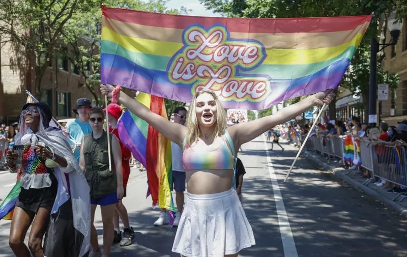 A participant carries a "Love is love" banner during the 51st LGBTQ Pride Parade in Chicago, Illinois, on June 26, 2022. - The Pride Parade returned to the Lakeview and Uptown neighborhoods after a three year hiatus due to the coronavirus pandemic. (Photo by KAMIL KRZACZYNSKI / AFP)