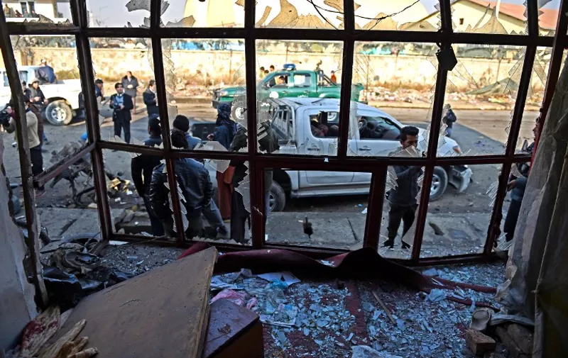 Afghan security force personnel look through the broken windows of a bakery at the site of a suicide car bomb near the international airport in Kabul on December 28, 2015. A Taliban bomber has detonated an explosives-packed vehicle near Kabul airport in an attack on a NATO convoy, killing one civilian a day after Pakistan's army chief visited the Afghan capital in an effort to revive peace talks.Four other civilians were wounded in the early morning attack, which comes amid a worsening security situation in Afghanistan as the Taliban step up their nationwide offensive. "The bombing occurred near Kabul airport... We are finding out more details," Gul Agha Rohani, Kabul deputy police chief, told AFP. AFP PHOTO / SHAH Marai / AFP / SHAH MARAI