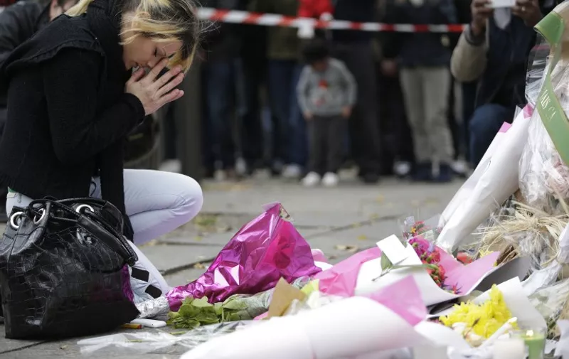 TOPSHOTS
A woman prays at messages and flowers left at a rail cordon close to the Bataclan theatre in the 11th district of Paris on November 14, 2015, the day after a series of attack on the city resulting in the deaths of more than 128 individuals. Some 80 people were gunned down at the Bataclan theatre in Paris late November 13, during a concert by the US band Eagles of Death Metal. AFP PHOTO / KENZO TRIBOUILLARD