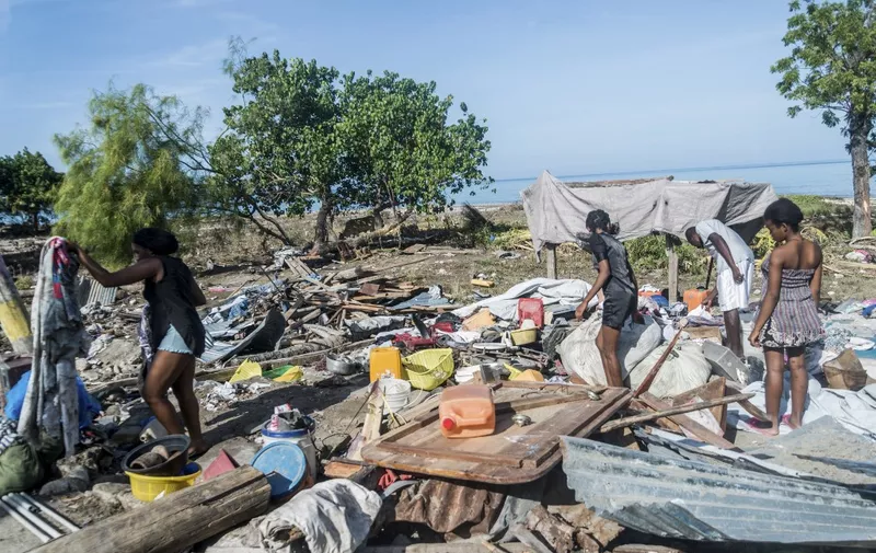 People clean up what remains of their home, as the small houses near the coast were severely damaged by the overflow of the sea immediately after the earthquake in Port-a-Piment, Haiti on August 16, 2021. - The death toll from Haiti's powerful earthquake jumped to over 1,200 on August 15, 2021, as crews desperately dug through collapsed buildings for survivors in the Caribbean nation still reeling from its president's assassination. In Les Cayes, as in other hard-hit cities on the southwestern peninsula, most of the population spent the night sleeping outdoors in front of their houses -- or what remained of them -- amid fears of new aftershocks. (Photo by Reginald LOUISSAINT JR / AFP)