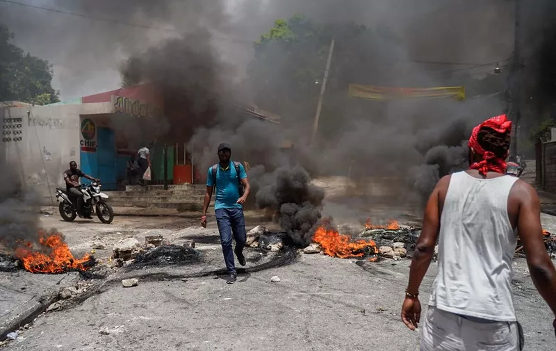 Haitians protesting high prices and shortages burn tires on a street of Port-au-Prince on July 13, 2022. - Soaring prices, food and fuel shortages and rampant gang violence are accelerating a brutal downward spiral in the security situation in the Haitian capital Port au Prince,  and threatening the humanitarian aid the increasingly desperate population relies on. (Photo by Richard Pierrin / AFP)