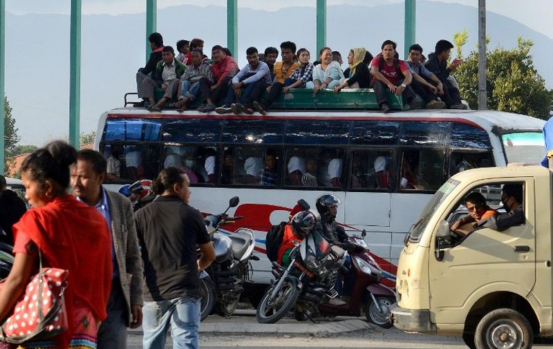 To go with story 'Nepal-quake-aid, FOCUS' by Paavan MATHEMA

In this photograph taken on October 15, 2015, Nepalese commuters travel atop a public bus as fuel rations are implemented, in Kathmandu.  Nearly six months after a 7.8-magnitude quake killed nearly 8,900 people and destroyed about half a million homes, thousands of survivors are still living in tents and other temporary shelters, dependent on aid. But the three-week blockade of a major border checkpoint by protesters who reject Nepal's new constitution has sparked a fuel shortage and nationwide rationing, with vital supplies unable to get through.   AFP PHOTO / Prakash MATHEMA