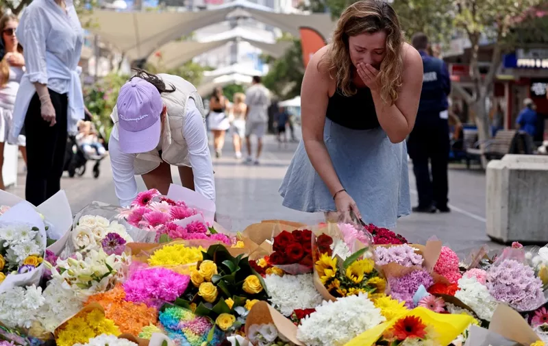 People react as they leave flowers outside the Westfield Bondi Junction shopping mall in Sydney on April 14, 2024, the day after a 40-year-old knifeman with mental illness roamed the packed shopping centre killing six people and seriously wounding a dozen others. (Photo by DAVID GRAY / AFP)
