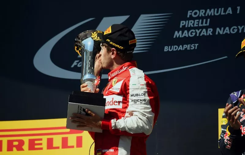 Ferrari's German driver Sebastian Vettel kisses the trophy as he celebrates on the podium winning the Hungarian Formula One Grand Prix at the Hungaroring circuit  near Budapest on July 26, 2015. 
 AFP PHOTO / ATTILA KISBENEDEK