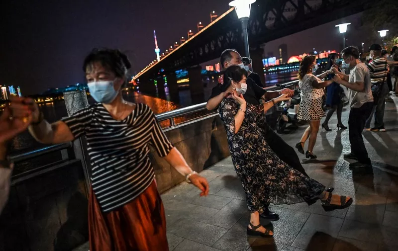 People wearing facemasks dance in a park next to Yangtze River in Wuhan, China's central Hubei province on May 27, 2020. - China's foreign minister on May 24 said the country was "open" to international cooperation to identify the source of the disease, but any investigation must be led by the World Health Organization and "free of political interference". (Photo by Hector RETAMAL / AFP)